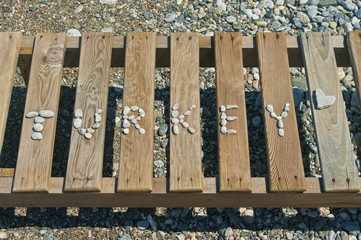 word lined with small pebbles on wooden sunbed