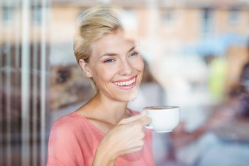Happy blonde woman drinking a cup of coffee