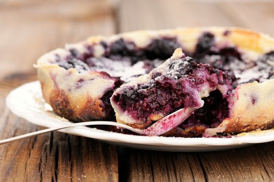 French pie clafoutis with cherry and spoon in white plate