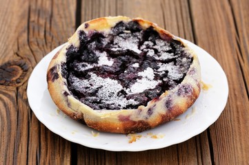 French pie clafoutis with berries and icing sugar in white round