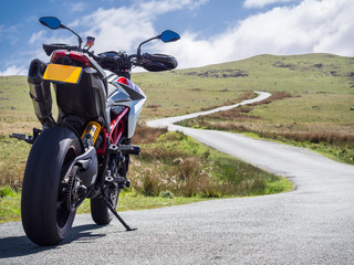 Fototapeta premium Motocykl typu supermotard skierowany w stronę krętej drogi