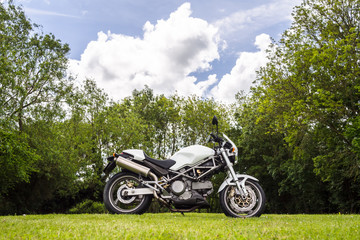 Fototapeta na wymiar One motorcycle in field with spring forest in its background