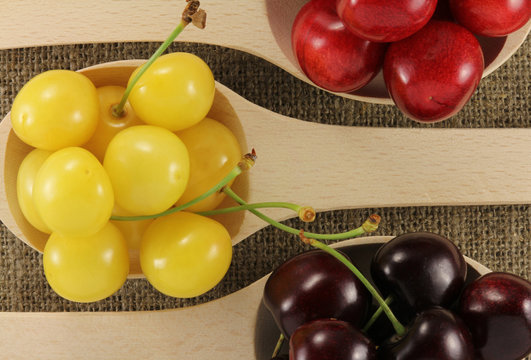 Colorful cherries in a wooden spoon on a natural fabric