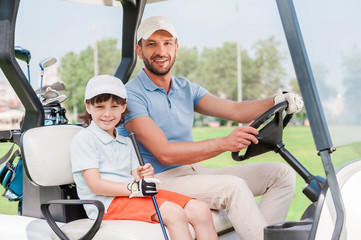 Father and son in golf cart. 