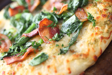 Pizza topped with bacon and greens