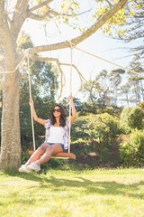 Pretty brunette swinging in park 
