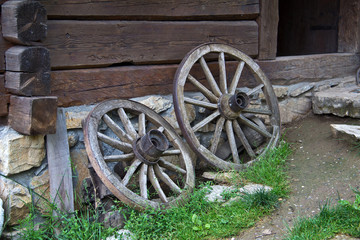 Fototapeta na wymiar Old Wagon Wheel / Old Wagon Wheel against an Old Historic House Wall.