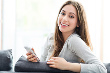 Woman using mobile phone on sofa
