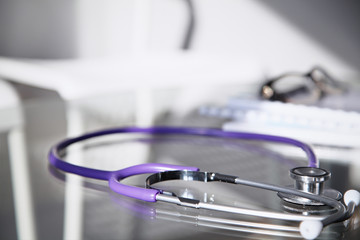 Purple stethoscope on the glass desk