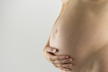 Closeup of pregnant woman holding her bare swollen belly