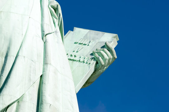 July 4, 1776 Independence Day tablet held by the Statue of Liberty close-up against bright blue sky