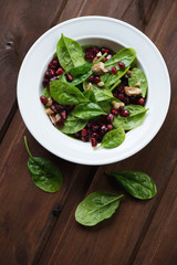 Glass plate with spinach, pomegranate and walnuts salad