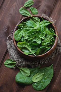 Wooden bowl with fresh spinach leaves, high angle view