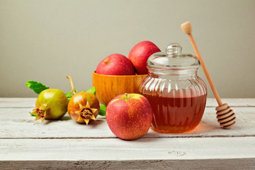 Honey jar and fresh apples with pomegranate on wooden board