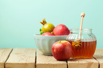 Apple and honey on wooden table over blue background