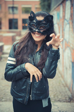 Portrait of young woman in cat mask standing outdoors