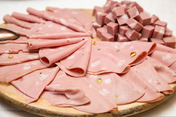 Mortadella a fette e a cubetti su piatto di legno