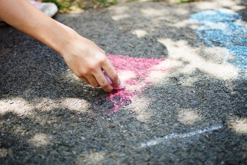 Children draw in the park with chalks of various colors. Selective focus on hand.
