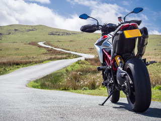 Obraz premium A supermotard type motorcycle facing towards the winding road ahead