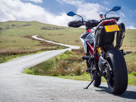 A supermotard type motorcycle facing towards the winding road ahead