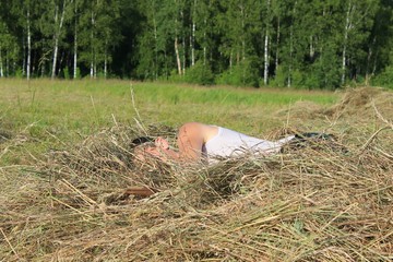 Молодой человек спящий на поле на сене