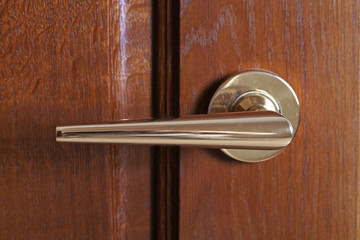 metal door handle on a brown door close up