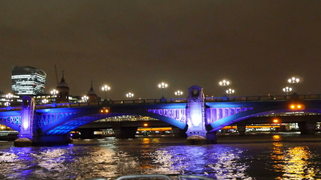 The calm and busy bridge in London at night. While cruising along the Thames river