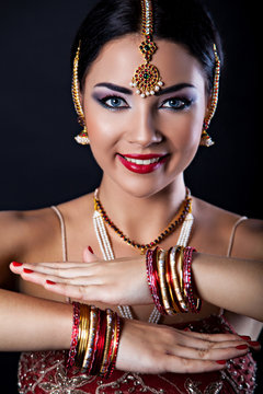 Smiling young woman with oriental makeup and Indian Jewelry