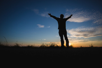 Fototapeta na wymiar silhouetted man standing in sunset sky