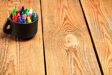 Naklejka premium Crayons in a mug on a wooden table