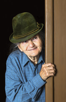 Elderly Woman With Hat Peeking Through Doorway At Home