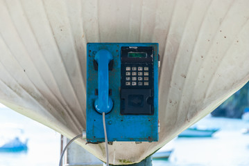 Call box with blue phone on beach in summer season. Vintage telephone booth in shell shade. Image is filtered for retro effect