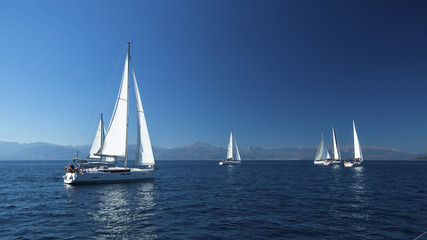 Naklejka na ściany i meble Ship yachts with white sails in the open Sea. Boats in sailing regatta. Sailing yacht race.