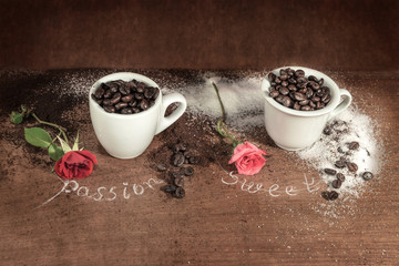 Tazzine con chicchi di caffè con zucchero e rose su legno grezzo.