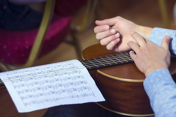 Young male's hands and guitar with musical scores