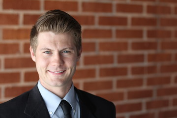 Portrait of an attractive young businessman in urban background wearing blue suit a necktie. Blonde...