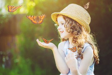 Laughing little girl with a butterfly on his hand. Happy childho