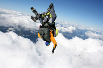 Fototapeta na wymiar Two skydivers in free fall on a sunny day in cloudy sky head down