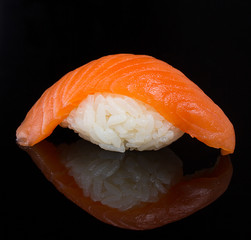 Salmon sushi nigiri clodeup over black background with refelction