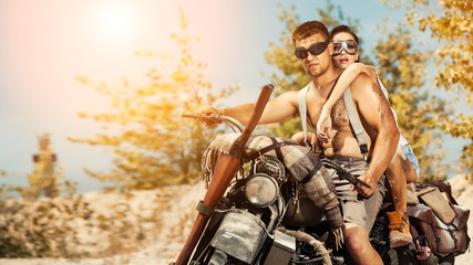 Fototapeta na wymiar Sexy couple of bikers with guns on the summer background.