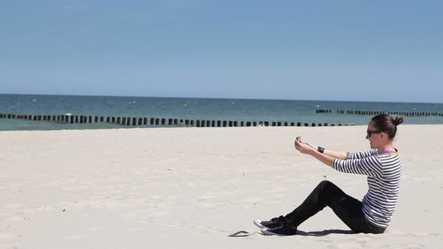 Woman uses a smartphone to video a beautiful view at the beach