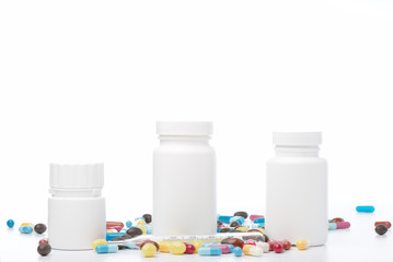 White pill bottle and colorful pills on white background