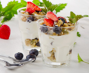 Granola with yogurt and fresh berries in glasses.