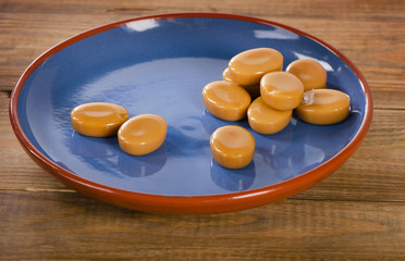 Caramel candies on  a rustic  wooden background.