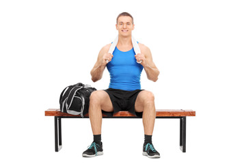 Obraz premium Young athlete posing seated on a wooden bench