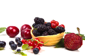 a lot of different berries near filled tartlets