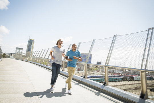 Two young men jogging along a bridge.
