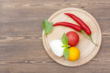 Mozzarella with herbs, noodles, fresh vegetables, chilli on a wooden round board, selective focus