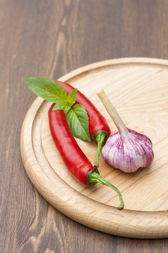 Red chilli pepper with green basil on wooden board