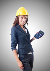 Female builder with calculator against gradient 